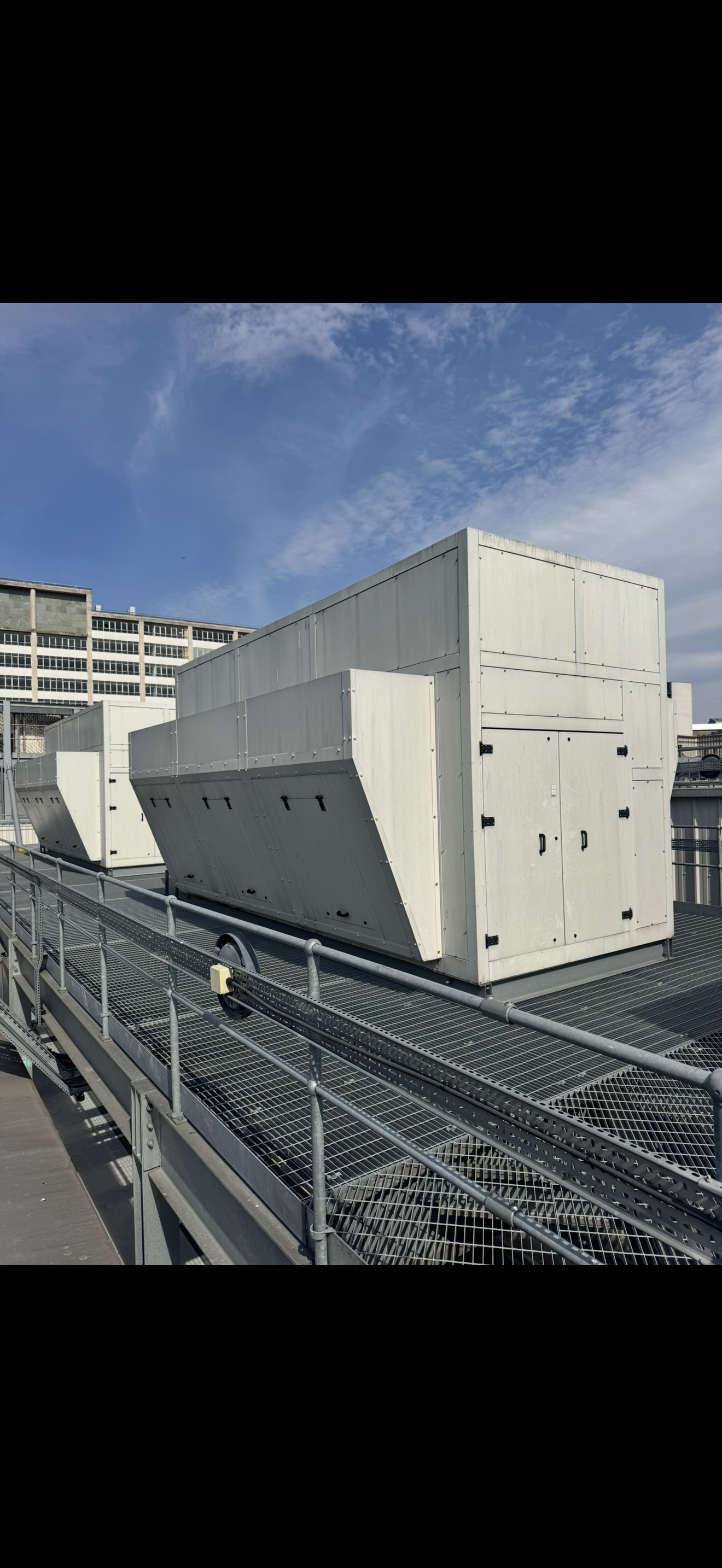 Rooftop cooling plant with large units beside a metal access walkway